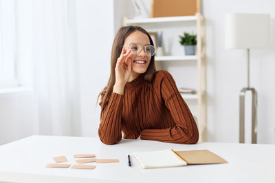 Portrait of young woman using mobile phone on table