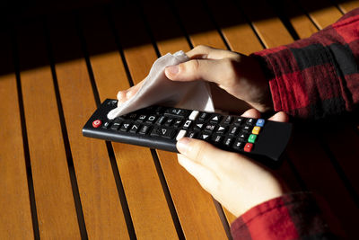 Hands disinfecting a tv remote.