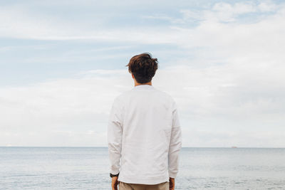 Rear view of man looking at sea against sky