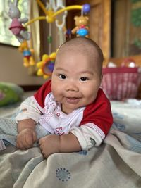 Portrait of smiling boy lying on bed at home