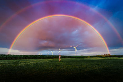 A small boy in a yard with a double rainbow