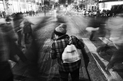 Rear view of man standing on road in city