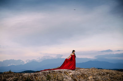 Young woman flying over mountain against sky