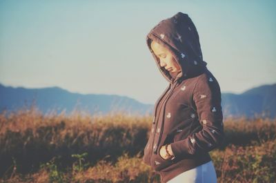 Side view of woman standing on field against sky