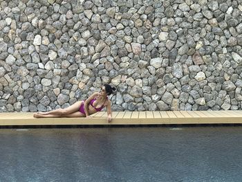 Woman sitting on rock by water
