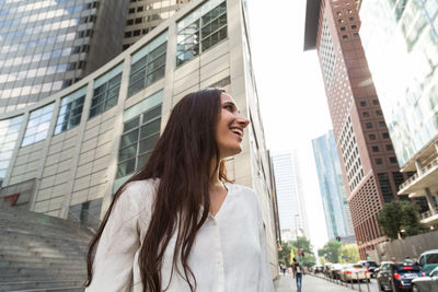 Woman looking away against buildings in city