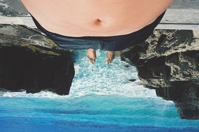 Upside down image of shirtless man lying on shore at beach