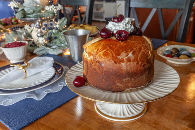 Panettone bread with cherries and whipped cream on a holiday table at christmas.