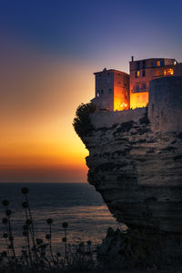 View of lighthouse in sea at sunset