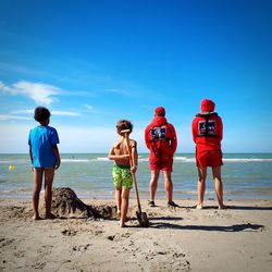 Rear view of people standing on beach