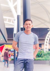 Portrait of smiling man leaning against pole