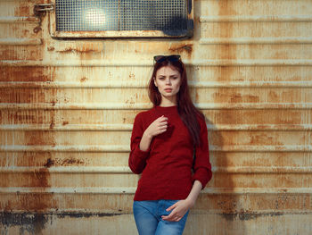 Portrait of young woman standing against wall