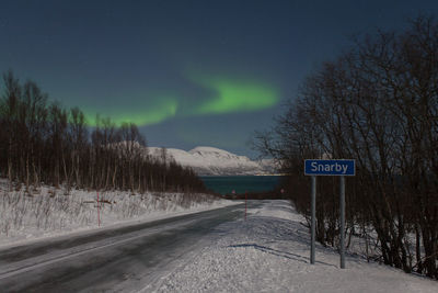 Empty road against aurora borealis during winter at night