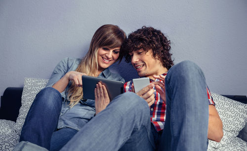 Young couple looking away while sitting on sofa at home