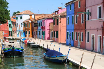 Boats moored on canal by colorful buildings at burano island