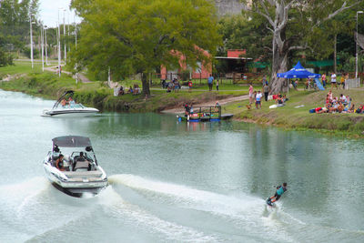 People on boats in water against trees