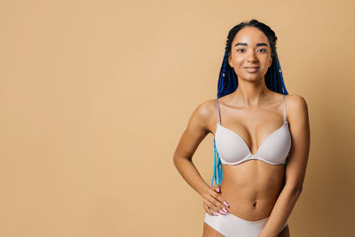 Portrait of young woman standing against yellow background