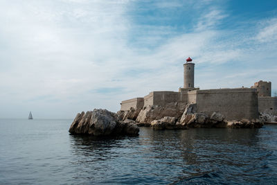 Lighthouse by sea against sky