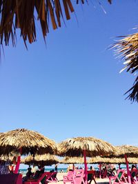 Low angle view of people on beach against clear sky