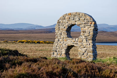 Stone structure on field against sky