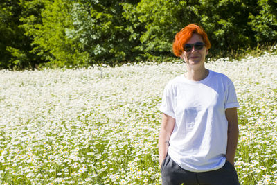 Women with sunglasses in field of daisy flowers during sunlight