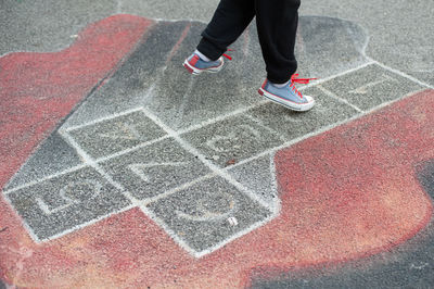 Low section of person playing hopscotch on street