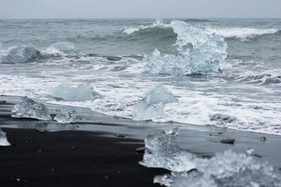 Ice blocks on diamond  beach, sea waves, black sand. jokulsarlon. atlantic ocean coast, iceland