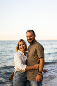 Portrait of smiling man standing at sea against sky