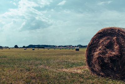 Hay bales on field against sky