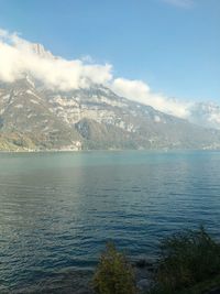 Scenic view of sea by mountains against sky