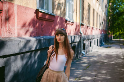 Portrait of young woman standing against building