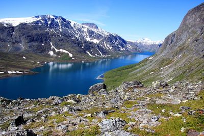 Scenic view of lake by snowcapped mountains against sky