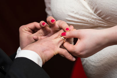 Midsection of bride putting ring in groom finger during wedding ceremony