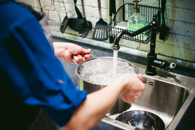 Woman holding container under faucet at kitchen