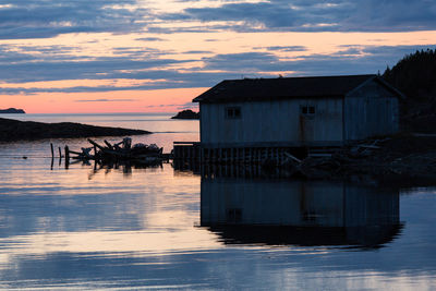 Building by sea against sky during sunset