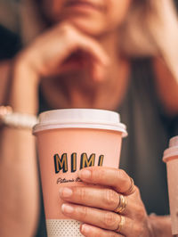 Midsection of woman having coffee in disposable cup