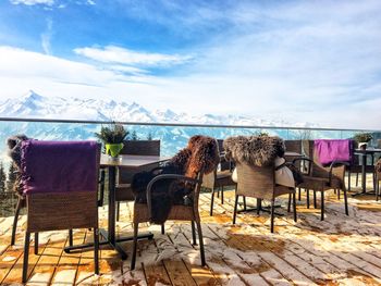 Chairs and table by sea against sky