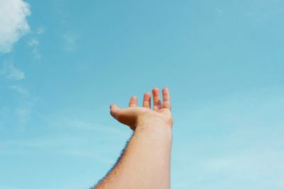 Cropped hand of woman against sky