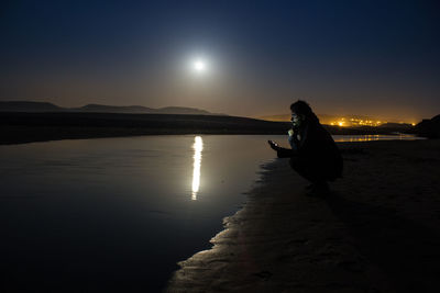 Reflection of people in water at sunset