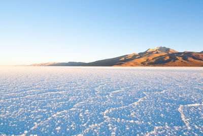 Scenic view of snowcapped mountains against clear blue sky