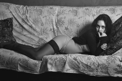 Portrait of young woman wearing lingerie lying on sofa at home