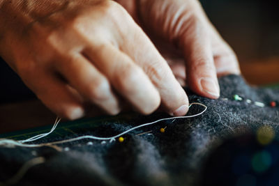 Close-up of cropped hands sewing textile in workshop