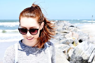 Portrait of woman wearing sunglasses standing at beach