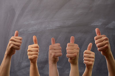 Close-up of hands over people against gray background