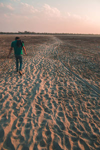 Rear view of woman walking on beach during sunset