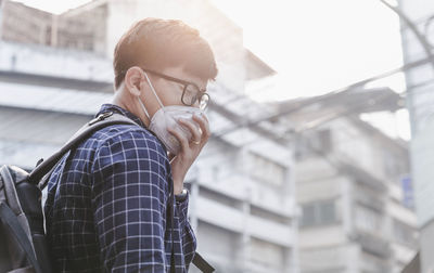 Side view of man wearing mask sneezing outdoors