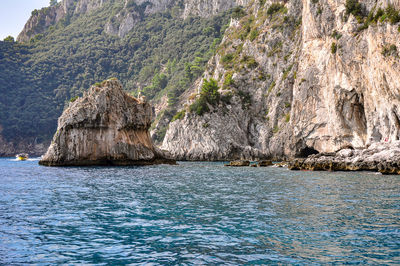 Rock formations by sea against mountain