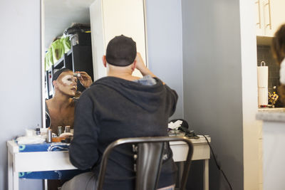 Young man applying drag makeup