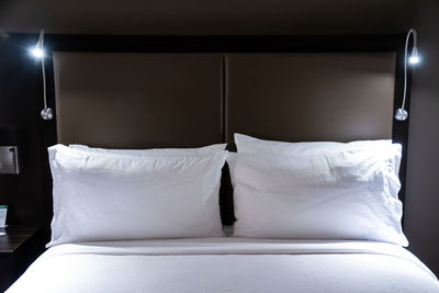 Midsection of illuminated lighting equipment on bed at home