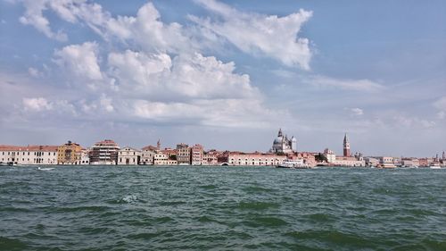 Buildings by sea against sky